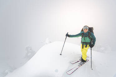 Junge Frau lächelt beim Skilanglauf auf einem verschneiten Gipfel in Squamish - CAVF82166