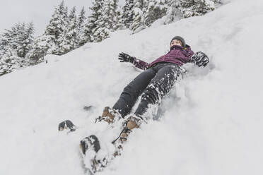 Junge Frau mit Hut rutscht schnell im Schnee bergab lustiges Gesicht - CAVF82172