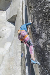 Climber looking at his feet in pink legging on The Nose in Yosemite - CAVF82192