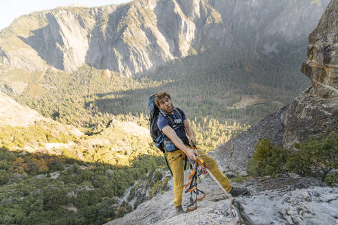 Mann jongliert mit Seil auf dem El Capitan und macht ein lustiges Gesicht mit Rucksack - CAVF82243