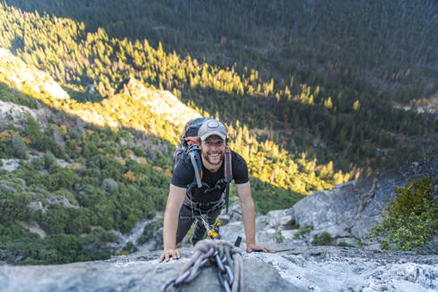 Mann lächelt, während er das Jugging-Seil am East Ledges El Capitan nach oben schaut - CAVF82246