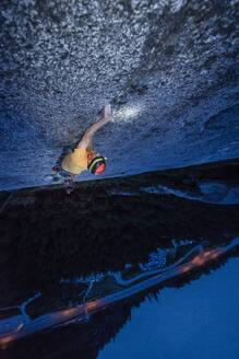 Draufsicht Mann beim Klettern in der Nacht über dem Meer und der Autobahn - CAVF82272