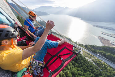 Zwei Männer sitzen auf einem Portaledge und genießen den Sonnenuntergang und die Aussicht in Squamish - CAVF82287