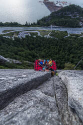 Draufsicht auf zwei Männer, die bei Sonnenuntergang auf einem Portaledge sitzen - CAVF82290