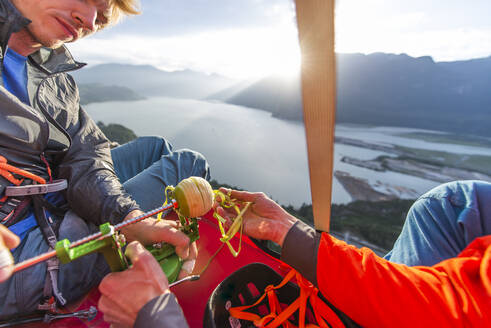 Zwei Männer mit einem Apfelschäler bei Sonnenuntergang auf einem Portaledge sitzend - CAVF82295