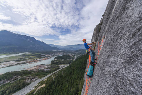 Mann schleppt Schleppsack beim Klettern auf Granit mit Blick auf Squamish - CAVF82309