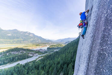 Man lead climbing granite Squamish with background view of valley - CAVF82328