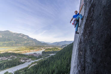 Man lead climbing granite Squamish with background view of valley - CAVF82329