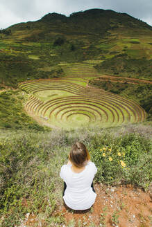 Eine junge Frau sitzt in der Nähe des berühmten peruanischen Ortes Moray in Peru - CAVF82399