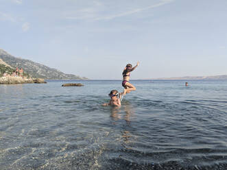 Zwei KinderSpielend und springend im Meer - CAVF82447