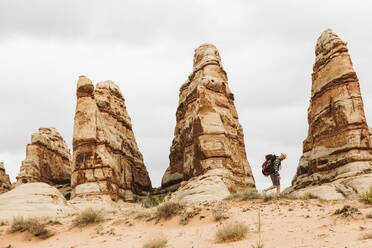 Wanderer mit Rucksack geht neben roten Sandsteintürmen in der Wüste von Utah - CAVF82454