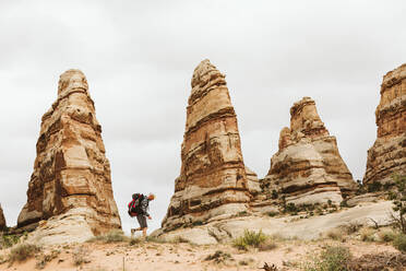 Männlicher Wanderer spaziert neben den Türmen der roten Felsen in der Wüste von Utah - CAVF82455