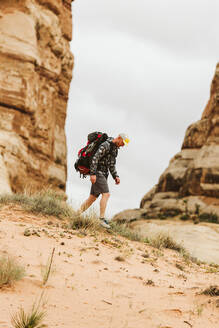 Wanderer in Tarnkleidung und großem Rucksack wandert im Sand in Utah - CAVF82456