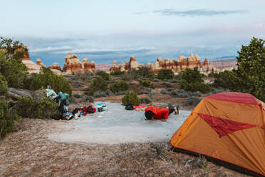 Eine Camperin macht Liegestütze auf ihrem Campingplatz in der Wüste von Utah - CAVF82481