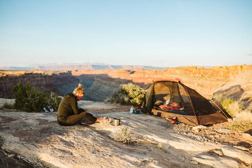 Camperin bereitet Essen neben dem Campingplatz mit Blick auf den Grand Canyon zu - CAVF82506