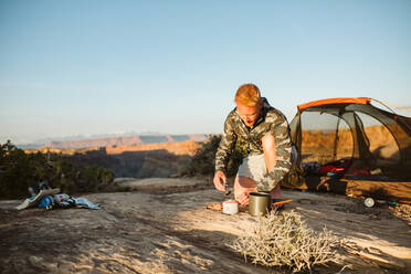 Camper in camo builds a camp stove whisper late preparing for dinner - CAVF82507