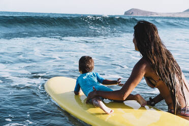 Junge Mutter und Sohn paddeln auf einem Surfbrett auf dem Meer - CAVF82553