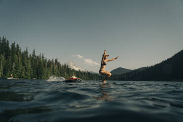 Eine junge Frau springt von einem Paddelbrett in den Lost Lake in Oregon. - CAVF82562