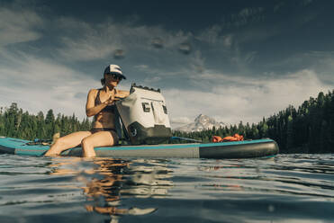 A young woman enjoys a standup paddle board on Lost Lake in Oregon. - CAVF82567