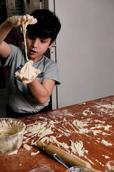 Child preparing pizza dough to make at home - CAVF82587