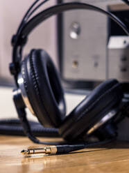 Black Hi-Fi headphones with a gold input jack on a wooden floor - CAVF82690