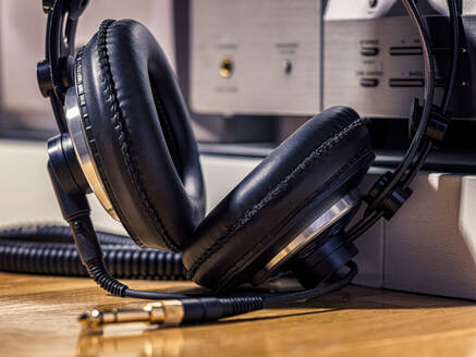Schwarzer Hi-Fi-Kopfhörer mit goldener Eingangsbuchse auf einem Holzboden - CAVF82691