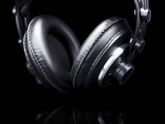 Black Hi-Fi headphones over a black reflective surface - CAVF82692