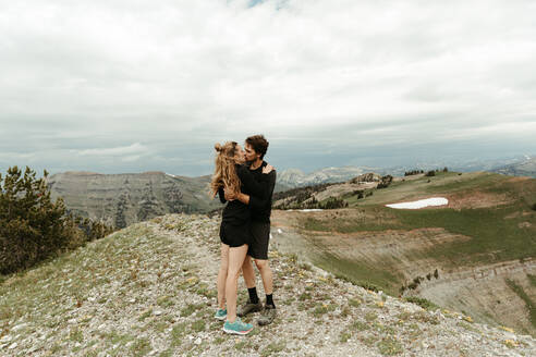 Neu verlobtes weißes Paar küsst sich auf einer Bergspitze in Wyoming - CAVF82715