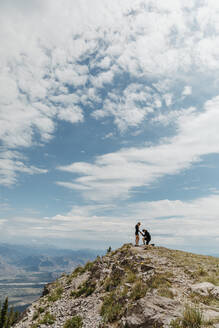Mann macht seiner Freundin auf dem Berg in Wyoming einen Heiratsantrag auf einem Knie - CAVF82718