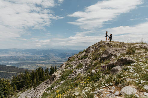 Freund kniet sich hin und macht auf einem Berg in Wyoming einen Antrag - CAVF82722