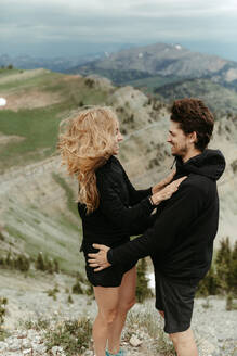 Glückliches weißes Paar verlobt sich auf einem windigen Berg in Wyoming - CAVF82724