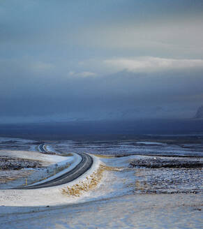 Ländliche Straße durch verschneites Gelände in Island - CAVF82787
