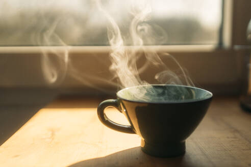 Steam rising from freshly prepared coffee in cup on table at home - GUSF03771