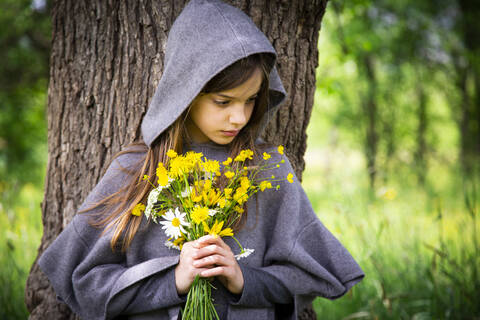 Mädchen hält einen Strauß gelber Wildblumen, lizenzfreies Stockfoto
