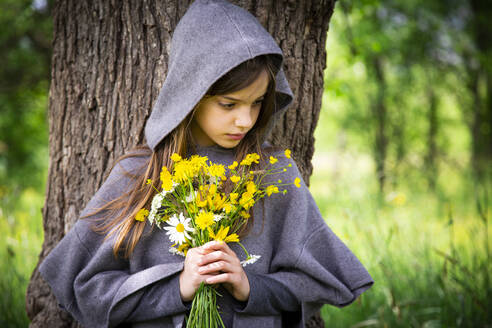 Girl holding bunch of yellow wildflowers - LVF08912