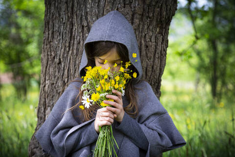 Girl smelling on bunch of yellow wildflowers stock photo