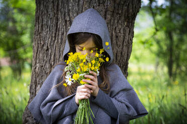 Girl smelling on bunch of yellow wildflowers - LVF08913