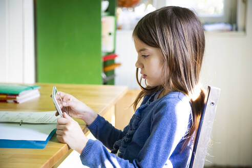 Girl doing homework and using tablet in kitchen at home - LVF08916