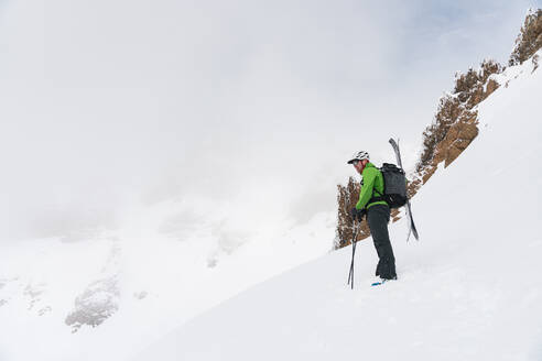 Skifahrer, der an der Spitze der Strecke steht und über die nebligen Berge blickt - CAVF82839