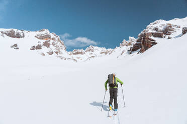 Sportler beim Skifahren in Richtung Berge an einem sonnigen Tag - CAVF82840