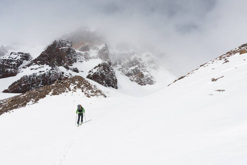 Skitourengeher im Hinterland gegen einen nebligen Berg - CAVF82841