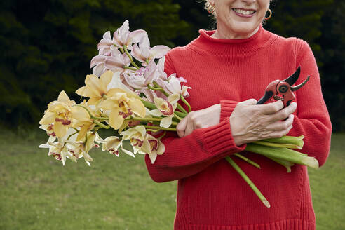 Lächelnde Großmutter mit frischen Schnittblumen aus dem Garten - CAVF82868