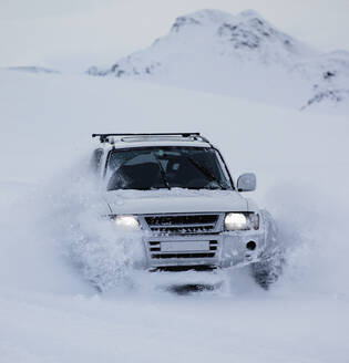 Maßgeschneiderter SUV pflügt durch verschneite Landschaft in Island - CAVF82971