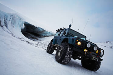 Individuell gestalteter Geländewagen vor einer Gletschereishöhle auf einem Gletscher - CAVF82976