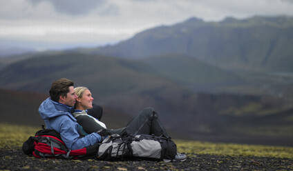 Hiking couple relaxing on mountainside in Iceland - CAVF82985