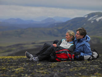 Hiking couple relaxing on mountainside in Iceland - CAVF82986