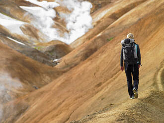 Junge Frau beim Wandern entlang eines Bergrückens im isländischen Hochland - CAVF82994