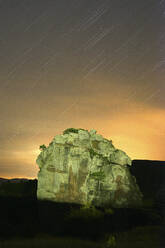 Spanien, Provinz Guadalajara, Chequilla, Sternenschweif über beleuchtetem Felsen in der Abenddämmerung - DSGF02045