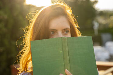 Porträt einer rothaarigen Frau mit grünem Buch - AFVF06358