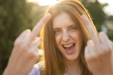 Portrait of laughing redheaded woman giving the finger - AFVF06361